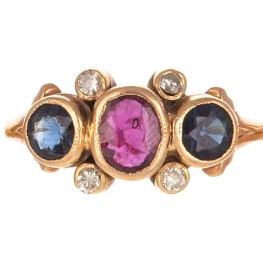 14K yellow gold ring featuring bezel set oval ruby and round sapphires with diamond accents